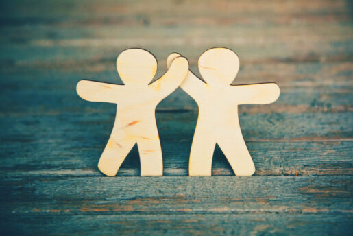 Two wooden figures high five.